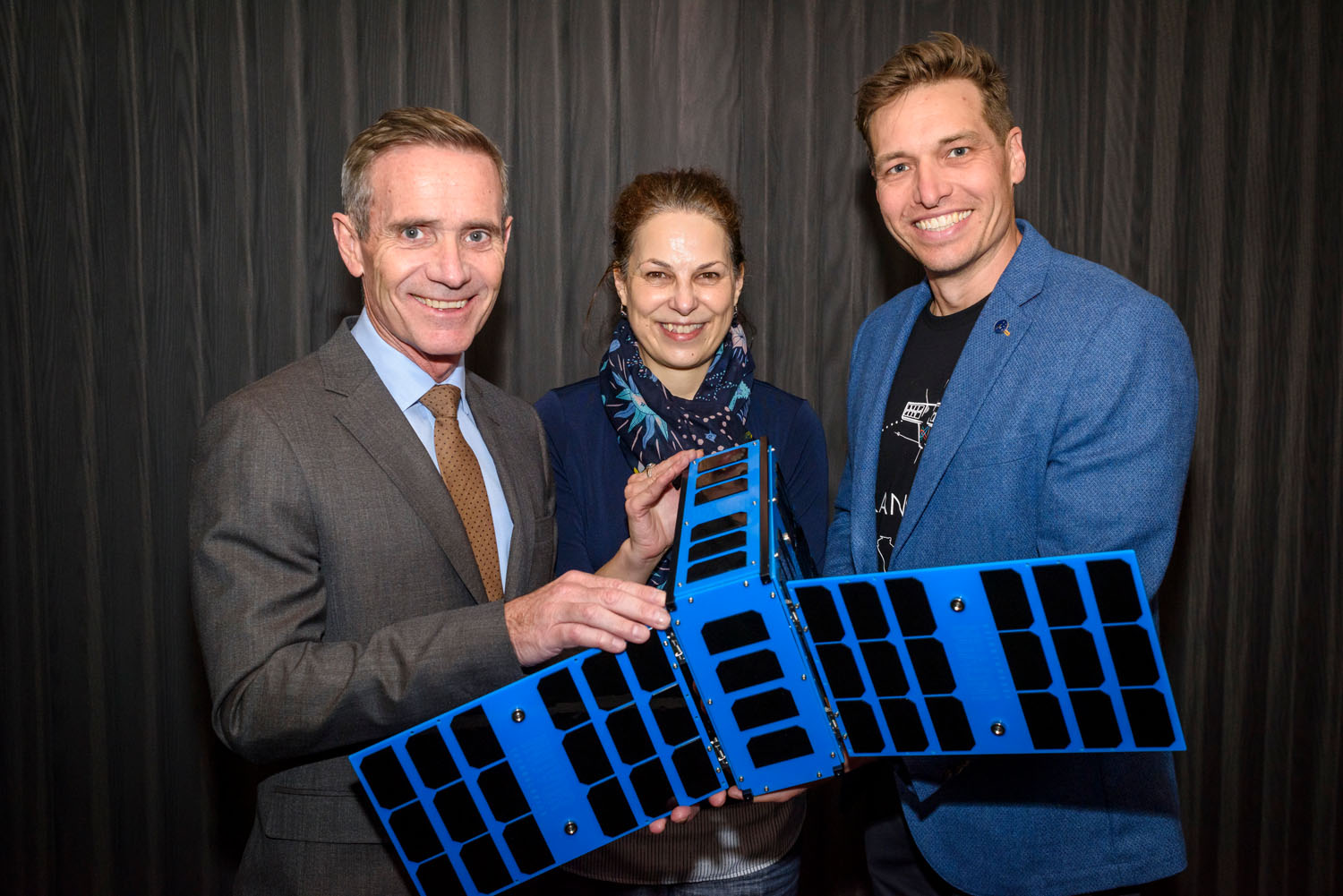 Two men and one woman holding a satellite demo